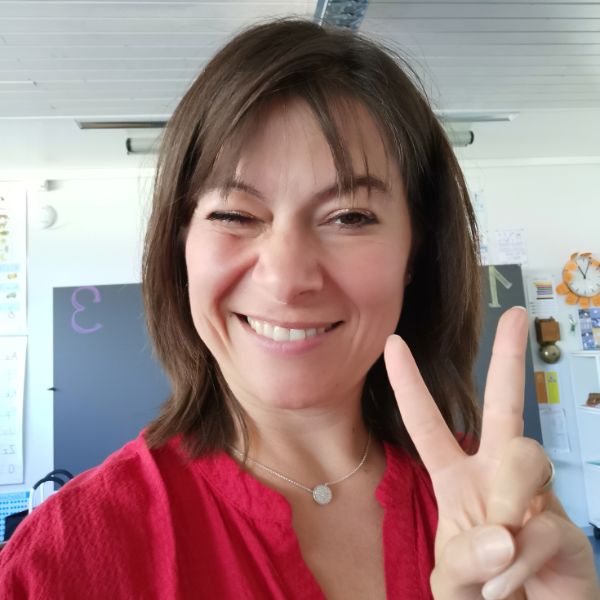 Andrea Hüppin lächelt, zwinkert und zeigt ein Peace-Zeichen – Symbol für einen positiven und entspannten Elternabend