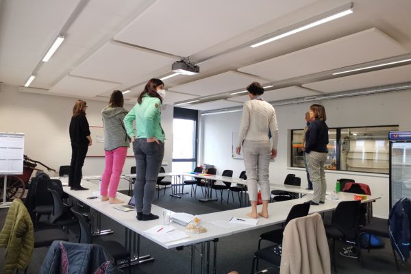Lehrerinnen stehen im Workshop auf den Tischen, um Perspektivwechsel in der Schule erlebbar zu machen